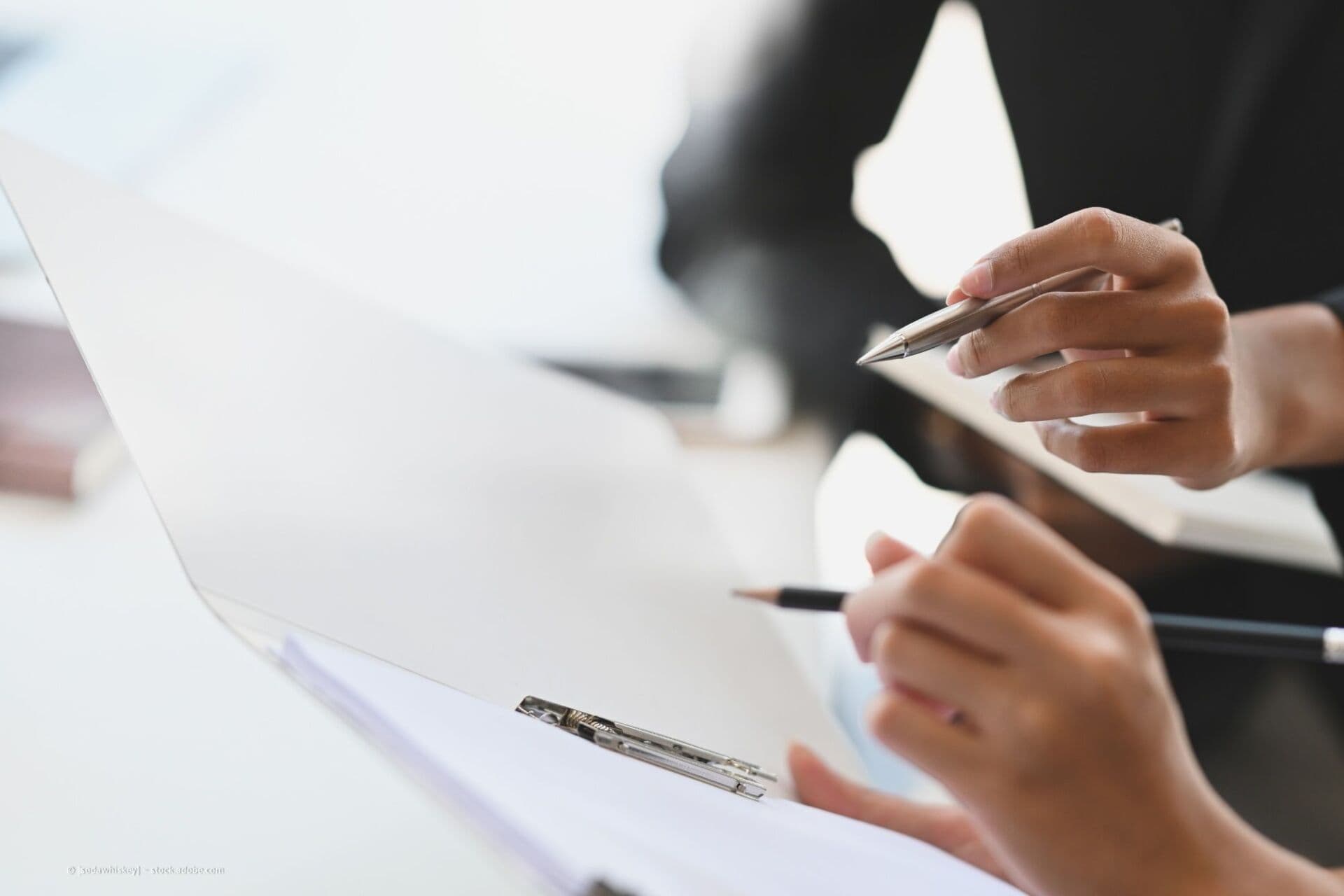 Zwei Personen besprechen Unterlagen mit Stift und Klemmbrett